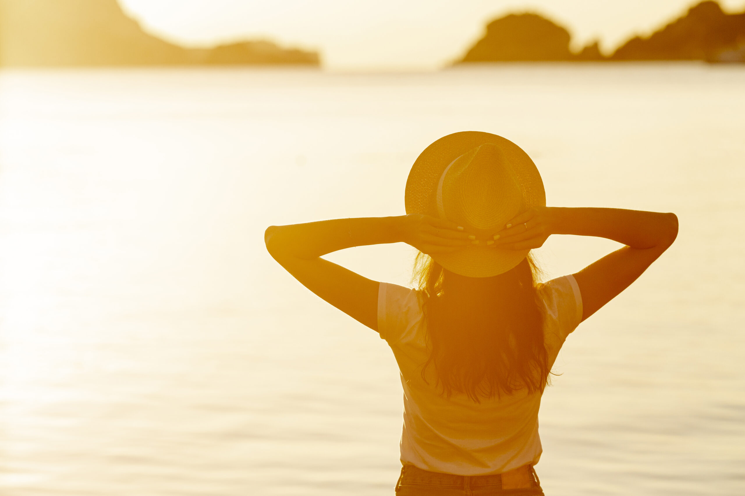 Mujer con sombrero frente al sol en un lago